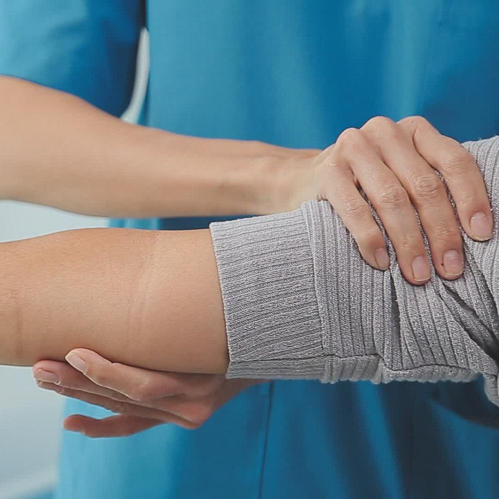 An image of massage therapist massaging a clothed arm - only the elbow joint and the therapist's hands and torso are visible.